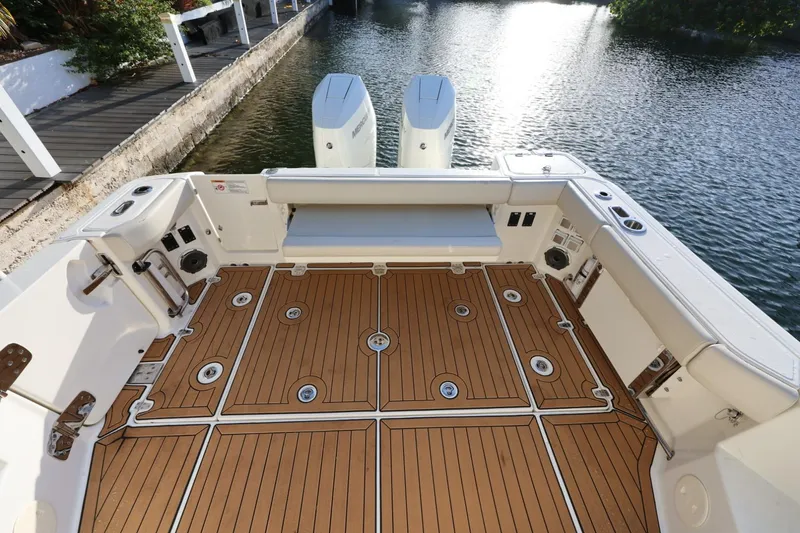 Slide: The Image of 2025 Boston Whaler 325 Conquest boat deck with teak flooring by the water. - 12