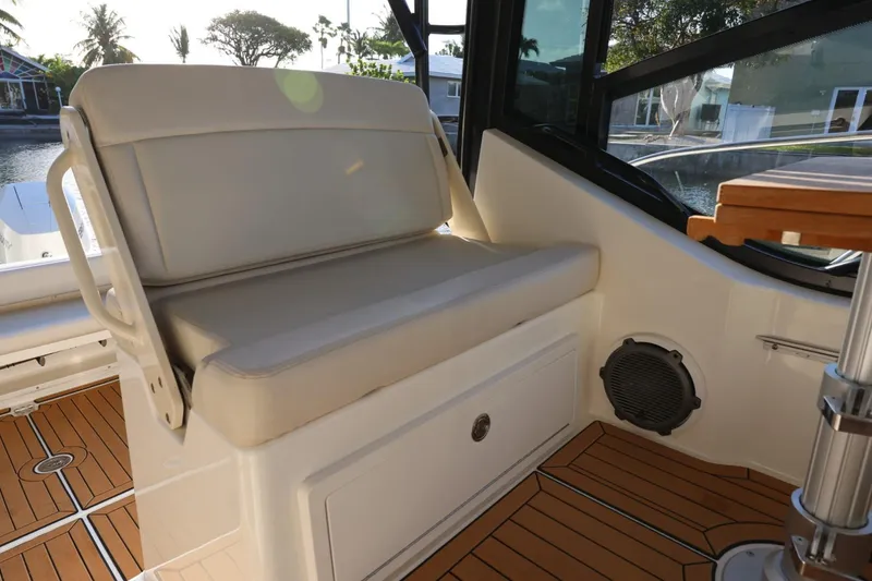 Slide: The Image of 2025 Boston Whaler 325 Conquest interior seating with teak flooring and window view. - 24