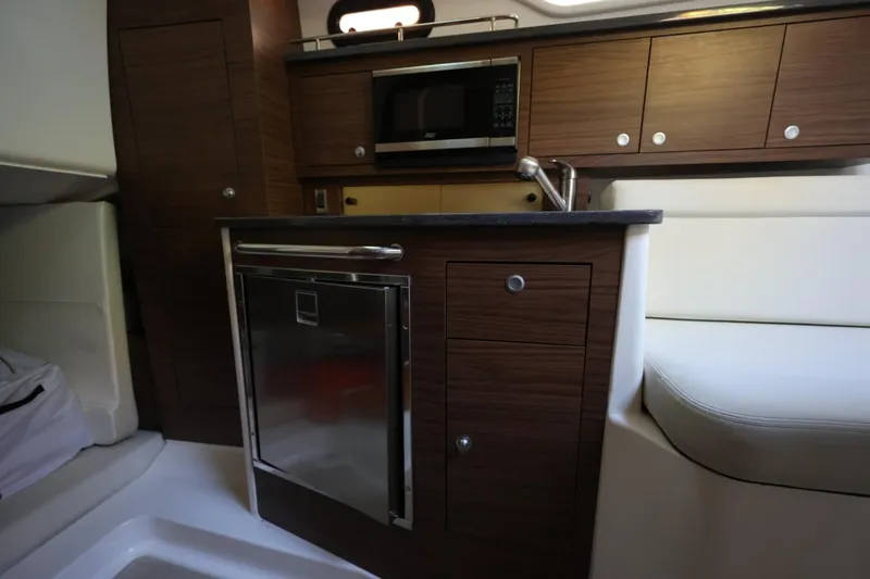 Slide: The Image of Interior of 2025 Boston Whaler 325 Conquest, featuring modern kitchenette with wood cabinetry. - 33