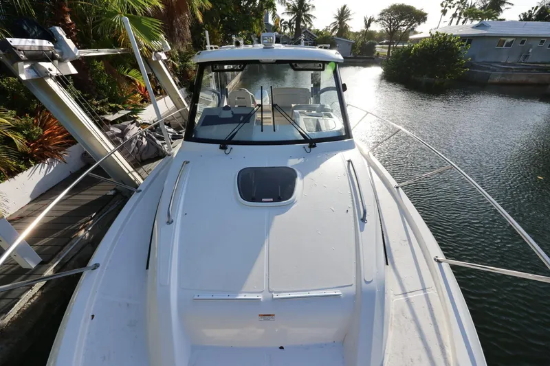 Slide: The Image of 2025 Boston Whaler 325 Conquest boat docked by tropical waterfront. - 37
