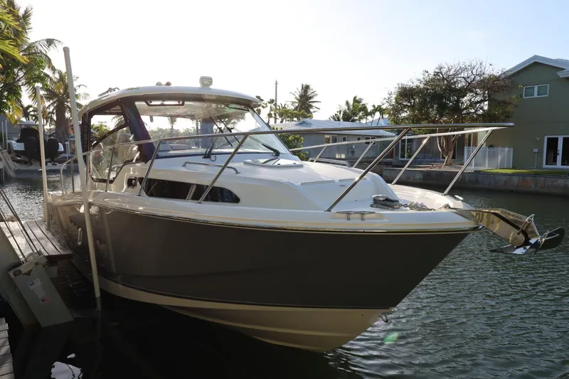 Slide: The Image of 2025 Boston Whaler 325 Conquest boat docked in a scenic canal setting. - 4