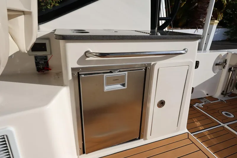 Slide: The Image of 2025 Boston Whaler 325 Conquest boat interior with stainless steel fridge and storage compartments. - 42