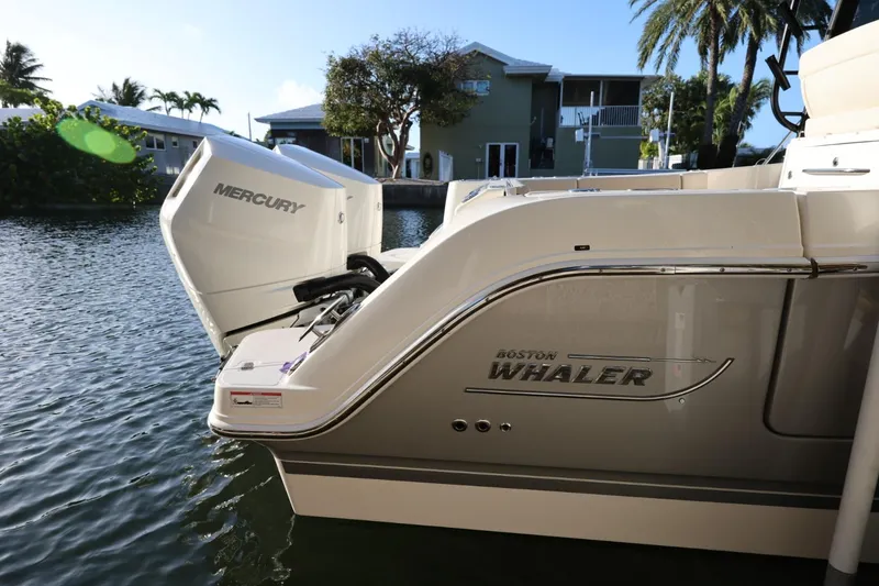 Slide: The Image of 2025 Boston Whaler 325 Conquest with Mercury engine docked by waterfront homes. - 6