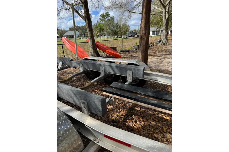Slide: The Image of Boat trailer for 2024 Ranger Tugs R-27, parked outdoors near red kayaks. - 101