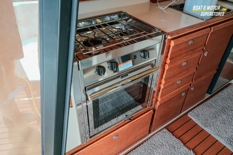 Slide: The Image of 2024 Ranger Tugs R-27 interior kitchen with stainless steel stove and wooden cabinetry. - 43