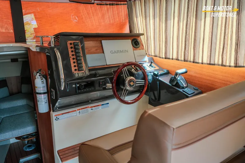 Slide: The Image of 2024 Ranger Tugs R-27 helm with Garmin navigation, wood accents, and striped curtains. - 48