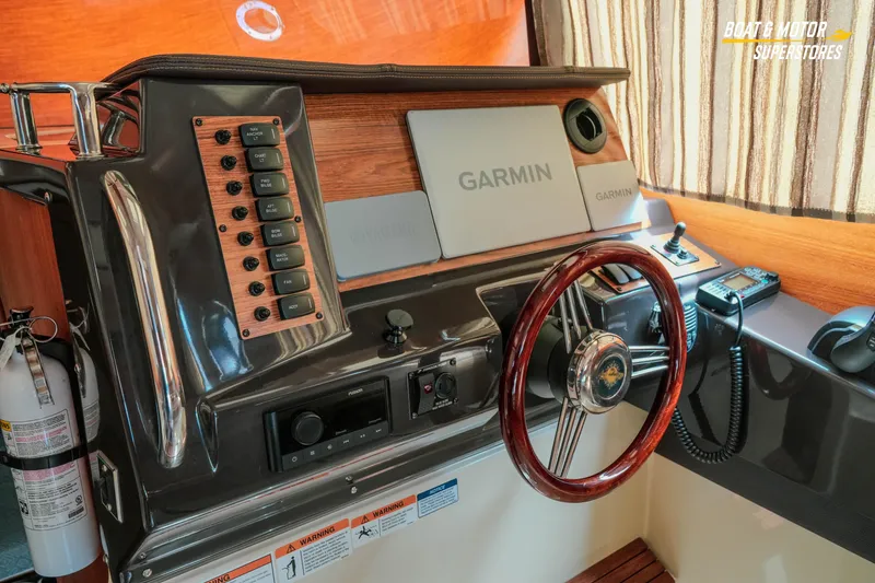 Slide: The Image of 2024 Ranger Tugs R-27 helm with Garmin navigation and wood-accented steering wheel. - 49