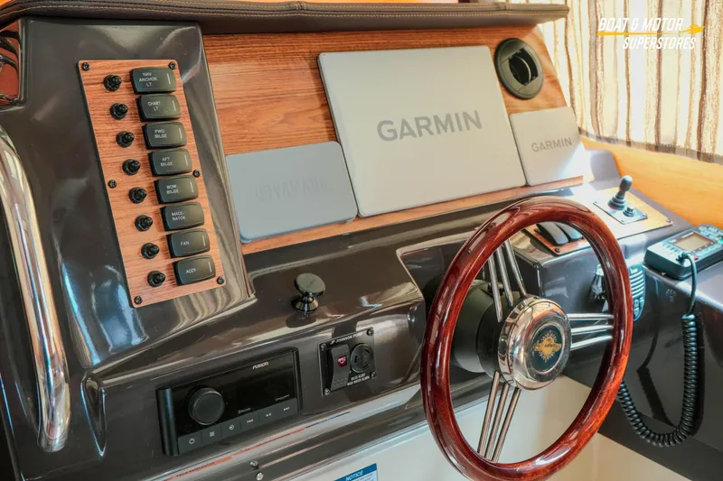 Slide: The Image of 2024 Ranger Tugs R-27 helm with Garmin navigation and wood-accented steering wheel. - 50