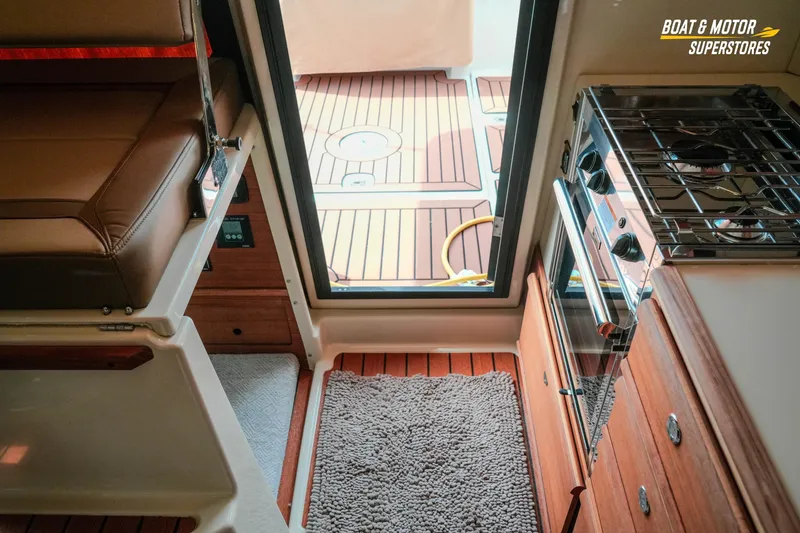 Slide: The Image of 2024 Ranger Tugs R-27 interior with stove, seating, and teak flooring. - 52
