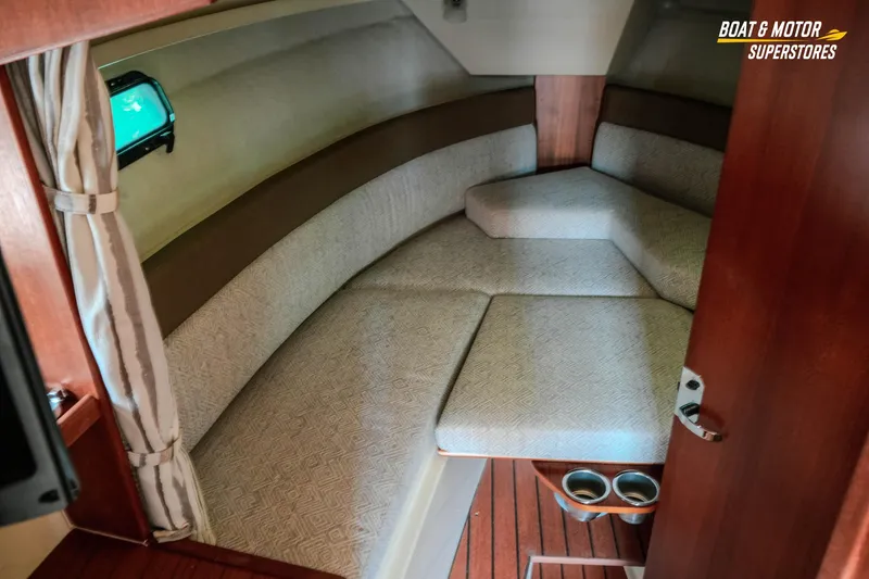 Slide: The Image of 2024 Ranger Tugs R-27 interior cabin with cozy seating and wooden accents. - 56