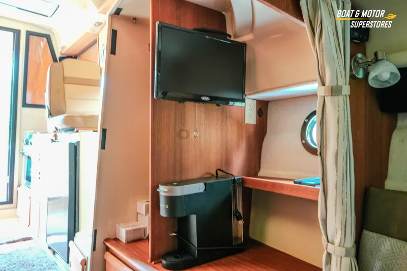 Slide: The Image of 2024 Ranger Tugs R-27 interior with TV, coffee maker, and porthole window. - 61