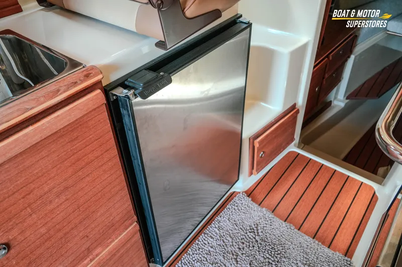 Slide: The Image of 2024 Ranger Tugs R-27 interior with stainless steel fridge and wooden cabinetry. - 64