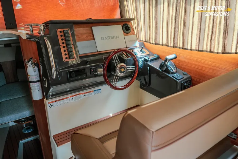 Slide: The Image of 2024 Ranger Tugs R-27 helm with Garmin navigation, wood accents, and leather seating. - 65