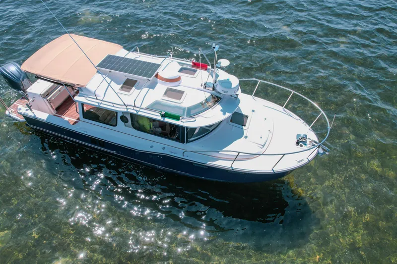 Slide: The Image of 2024 FML R27 LE boat cruising on clear water, featuring solar panels and a spacious deck. - 7