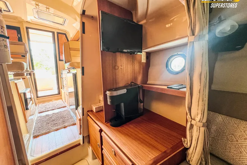 Slide: The Image of 2024 Ranger Tugs R-27 interior with TV, coffee maker, and cozy seating area. - 81