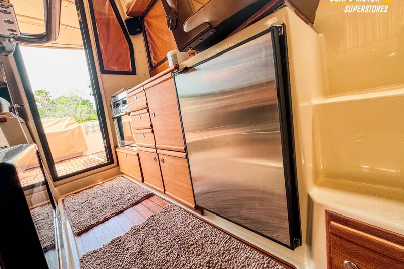 Slide: The Image of 2024 Ranger Tugs R-27 interior with wooden cabinetry and stainless steel appliances. - 88