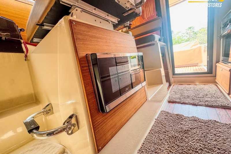 Slide: The Image of 2024 Ranger Tugs R-27 interior with wood paneling and modern appliances. - 89