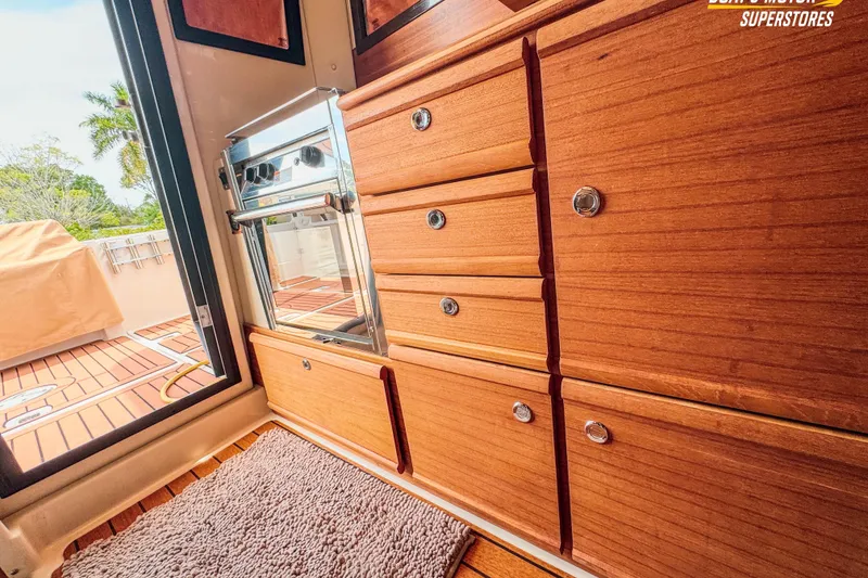 Slide: The Image of 2024 Ranger Tugs R-27 interior with wooden cabinetry and outdoor deck view. - 90