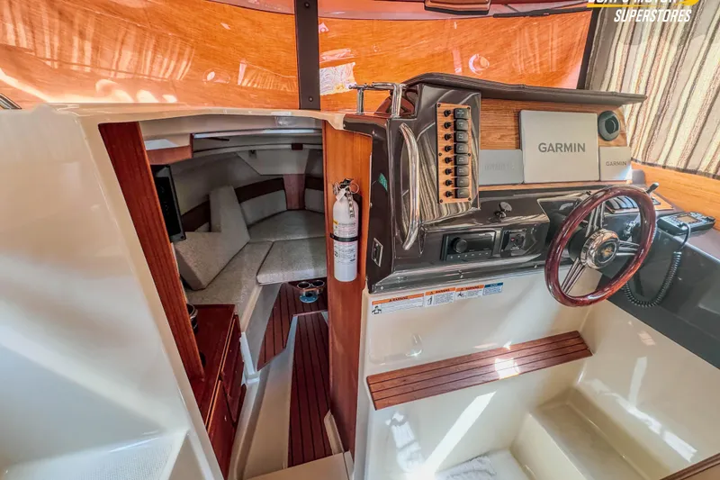 Slide: The Image of 2024 Ranger Tugs R-27 interior with helm, Garmin navigation, and cozy cabin space. - 93