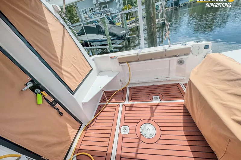 Slide: The Image of 2024 Ranger Tugs R-27 boat deck with teak flooring and tan covers, docked by water. - 95