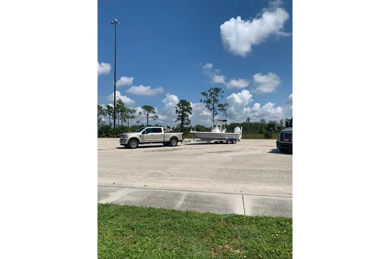 Slide: The Image of Truck towing a 2024 Ranger Tugs R-27 boat under a clear blue sky. - 96
