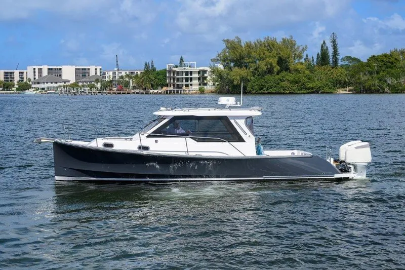 Slide: The Image of 2022 True North 34 boat cruising on a scenic waterway with buildings in the background. - 5