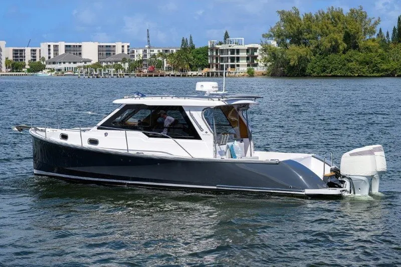 Slide: The Image of 2022 True North 34 boat cruising on a scenic waterway with modern buildings in the background. - 7