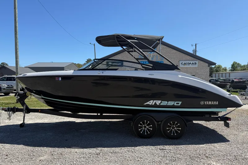 The Image of 2023 Yamaha Boats AR250 on trailer, sleek black design, parked outdoors. - 1