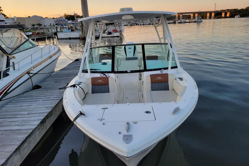 Slide: The Image of 2021 Cobia 240 Dual Console boat docked at marina during sunset. - 2