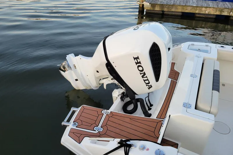 Slide: The Image of 2021 Cobia 240 Dual Console with Honda outboard motor on calm water. - 3