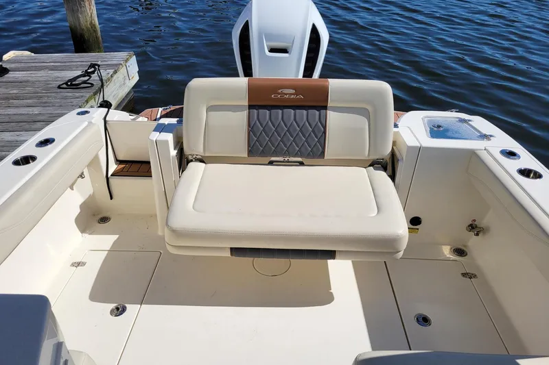 Slide: The Image of 2021 Cobia 240 Dual Console boat interior with cushioned seating by the water. - 5