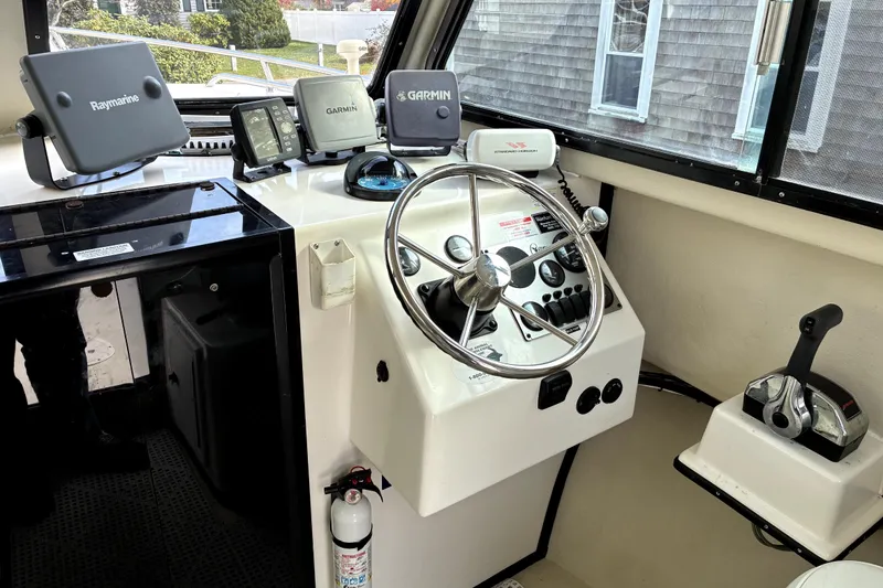 Slide: The Image of 2004 C-Hawk 25 Sport Cabin helm with steering wheel, navigation equipment, and controls. - 5