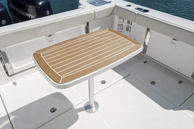 Slide: The Image of 2016 Boston Whaler 315 Conquest deck with wooden table and Mercury engines. - 24