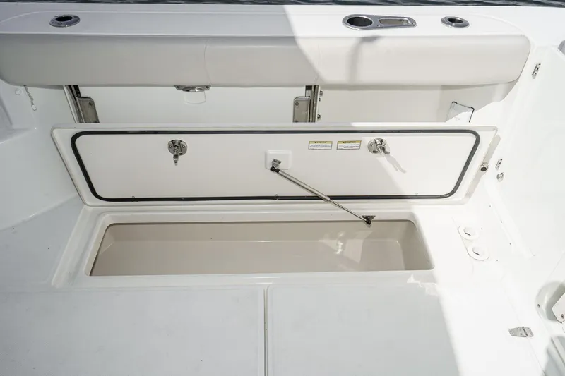 Slide: The Image of 2016 Boston Whaler 315 Conquest storage compartment with open hatch and cushioned seating. - 26