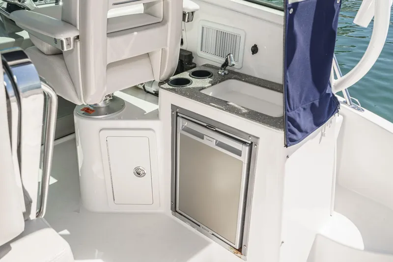 Slide: The Image of Interior of 2016 Boston Whaler 315 Conquest featuring a compact kitchenette with sink and fridge. - 40