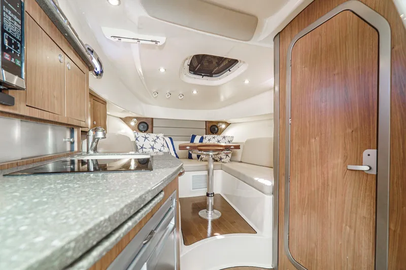 Slide: The Image of 2016 Boston Whaler 315 Conquest cabin interior with kitchenette and seating area. - 44