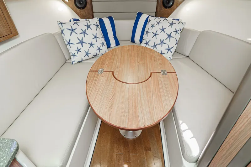 Slide: The Image of 2016 Boston Whaler 315 Conquest cabin interior with starfish pillows and wooden table. - 47