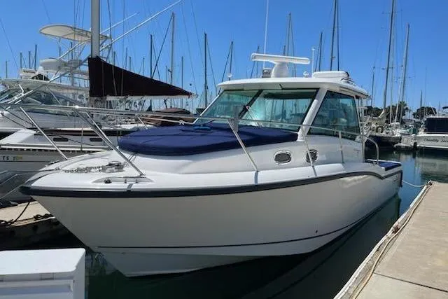 Slide: The Image of 2016 Boston Whaler 315 Conquest docked at a marina with sailboats in the background. - 49