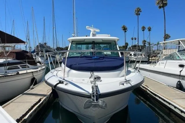 Slide: The Image of 2016 Boston Whaler 315 Conquest docked at marina, surrounded by sailboats and palm trees. - 50