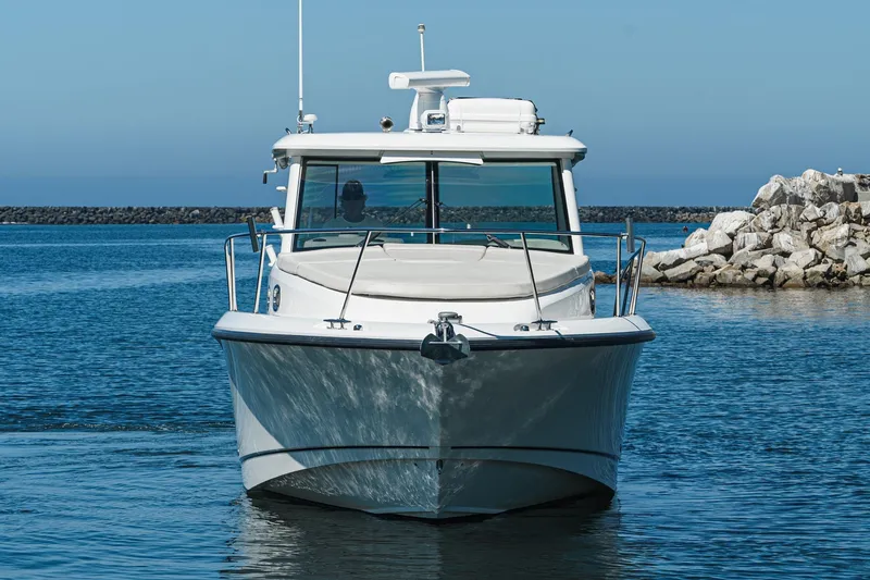 Slide: The Image of 2016 Boston Whaler 315 Conquest boat on calm water near rocky shore. - 7