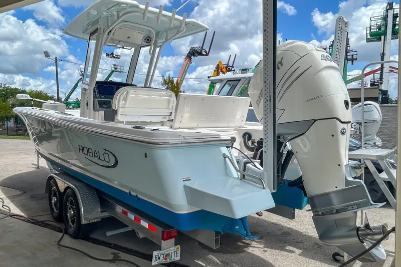 Slide: The Image of 2023 Robalo 266 Cayman boat with powerful outboard motor, parked on a trailer. - 1