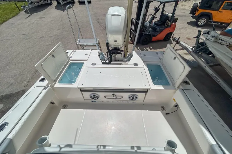 Slide: The Image of 2023 Robalo 266 Cayman boat deck with open storage compartments and motor. - 13