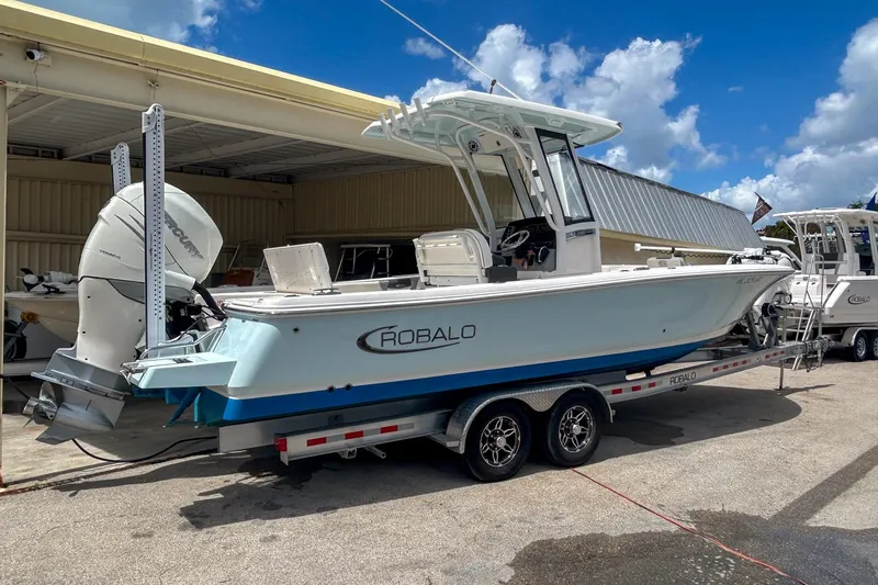 Slide: The Image of 2023 Robalo 266 Cayman boat on trailer, parked outdoors under a clear sky. - 2