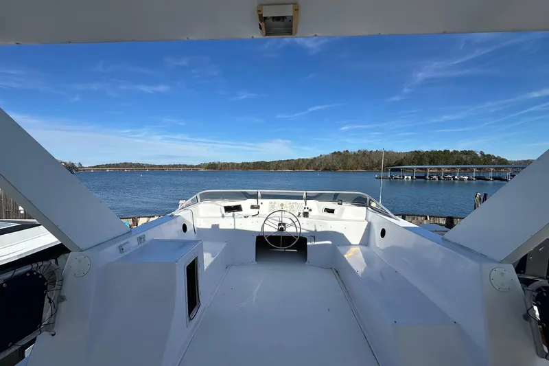 Slide: The Image of Helm of 2000 Sumerset 16x73 houseboat overlooking serene lake and marina. - 16
