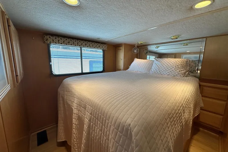 Slide: The Image of Cozy bedroom in 2000 Sumerset 16x73 houseboat with quilted bedding and wooden cabinetry. - 8