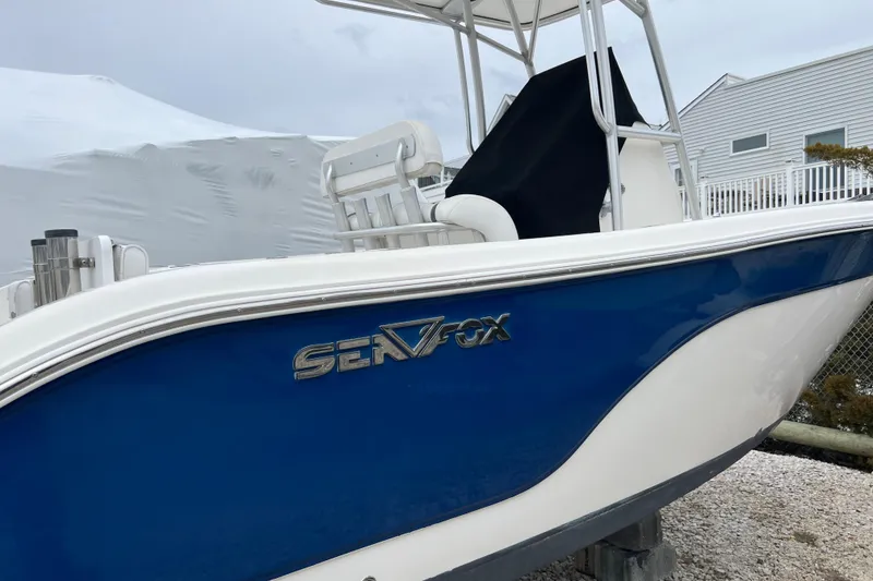Slide: The Image of 2010 Sea Fox 216 Center Console boat with blue and white hull, parked outdoors. - 5