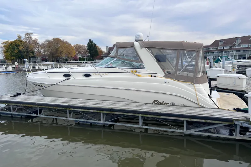Slide: The Image of 2002 Rinker Fiesta Vee 342 docked at marina, featuring sleek design and beige canopy. - 11