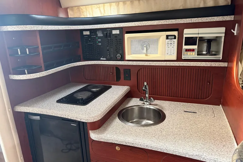Slide: The Image of 2002 Rinker Fiesta Vee 342 boat kitchen with stove, sink, microwave, and coffee maker. - 22
