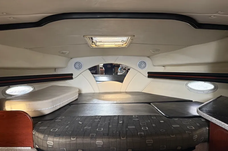 Slide: The Image of Interior cabin of 2002 Rinker Fiesta Vee 342 boat, featuring cozy seating and porthole windows. - 23