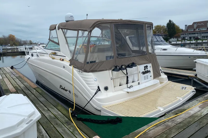 Slide: The Image of 2002 Rinker Fiesta Vee 342 docked at a marina, featuring a beige canopy. - 24